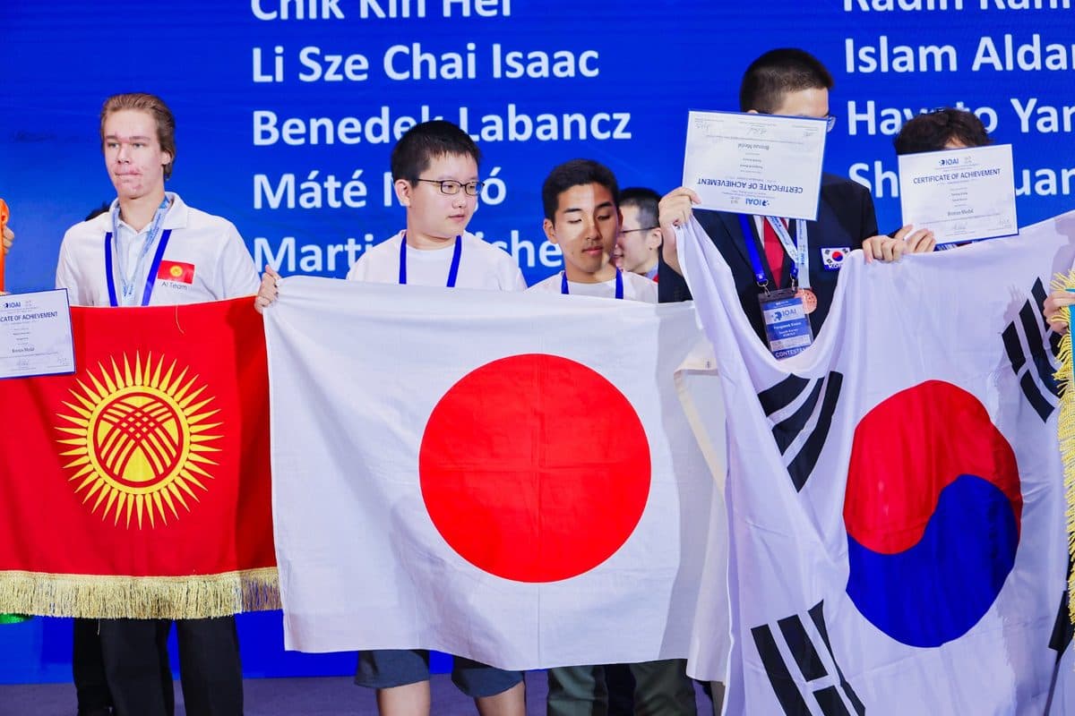 IOAI 2025 award ceremony: a student from Kyrgyzstan with a certificate beside national flags